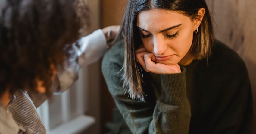 Empathy - Crop woman tapping shoulder and comforting upset female friend while sitting at home together